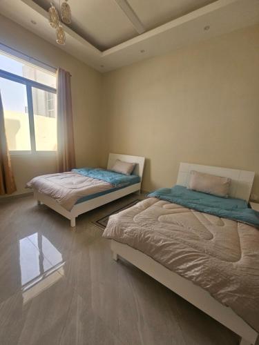 two beds in a room with a window at White Mountain House in Sharīyah