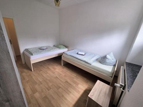 two beds in a small room with wooden floors at Ferienwohnung nahe Elsterwiese in Zeitz