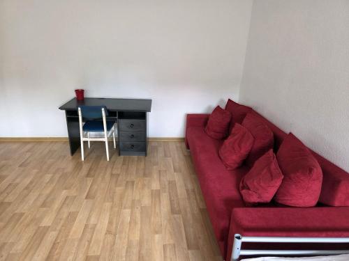 a living room with a red couch and a desk at Ferienwohnung nahe Elsterwiese in Zeitz