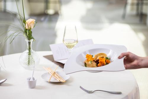 a plate of food on a table with a glass of wine at Small & Beautiful Hotel Gnaid in Tirolo