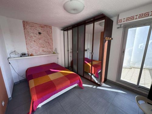 - une chambre avec un lit coloré et une fenêtre dans l'établissement Bel appartement 2 pièces + cabine avec terrasse vue port - FR-1-731-126, au Grau-du-Roi