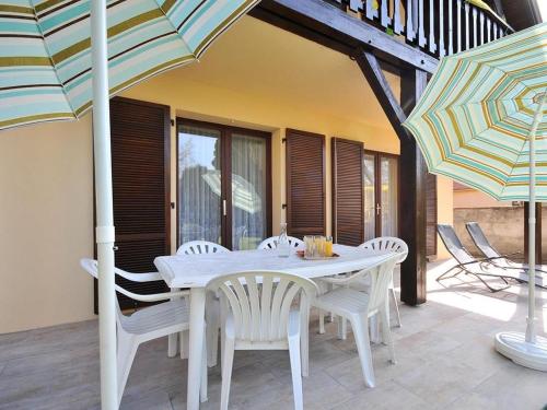 - une table et des chaises blanches avec des parasols sur la terrasse dans l'établissement Charmant gîte à Riquewihr avec jardin et parking privé - FR-1-744-45, à Riquewihr