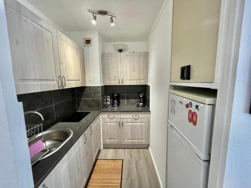 une cuisine avec des armoires blanches, un évier et un réfrigérateur dans l'établissement Appart P2 3 pers avec Garage & Piscine - FR-1-716-88, au Grau-du-Roi