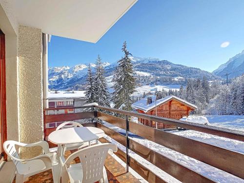 d'un balcon avec une table, des chaises et des montagnes enneigées. dans l'établissement La Clusaz - Apt 4 pers, 35 m², Balcon, Casier à skis - FR-1-818-107, à La Clusaz