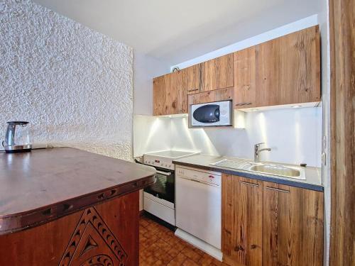 une petite cuisine avec un évier et un micro-ondes dans l'établissement La Clusaz - Appartement cosy 6 pers, balcon et parking - FR-1-818-104, à La Clusaz