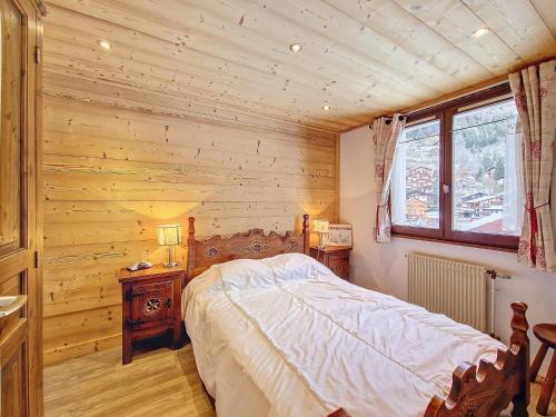 une chambre avec un lit et un mur en bois dans l'établissement La Clusaz - Appartement cosy 6 pers, balcon et parking - FR-1-818-104, à La Clusaz