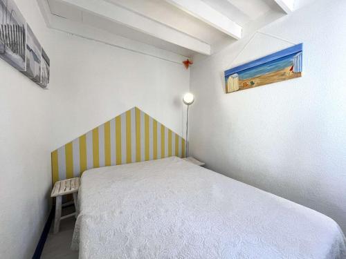 une petite chambre avec un lit avec une tête de lit rayée dans l'établissement Appartement 2 pièces climatisé avec parking - Gruissan - FR-1-229-898, à Gruissan