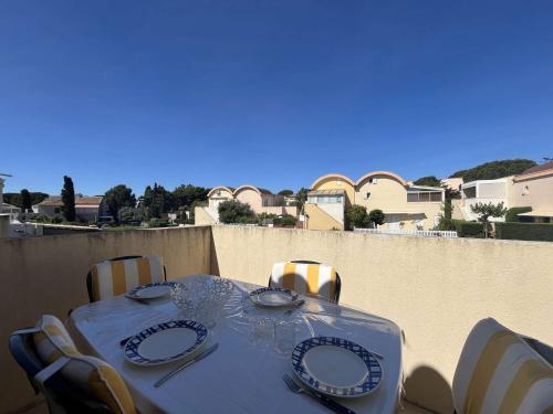 - une table avec des assiettes et de l'argenterie sur le balcon dans l'établissement Appartement 2 pièces climatisé avec parking - Gruissan - FR-1-229-898, à Gruissan