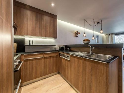 une cuisine avec des armoires en bois et un évier dans l'établissement Courchevel 1850 - Studio skis aux pieds, 4 pers, centre - FR-1-631-230, à Courchevel