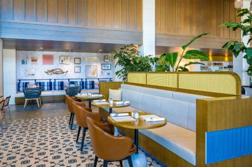 a restaurant with tables and chairs in a room at Inn at the Pier Pismo Beach, Curio Collection by Hilton in Pismo Beach