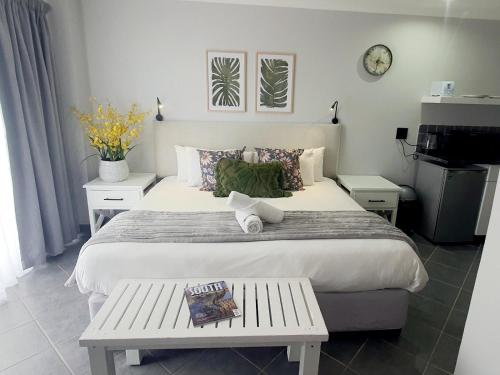 a bedroom with a large white bed with a bench at Point Village Hotel and Self Catering in Mossel Bay