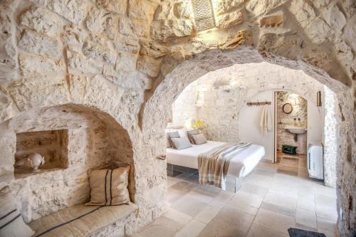 une chambre avec un lit dans un mur de pierre dans l'établissement Trulli cicale e olive - Le Case di Valentina, à Ceglie Messapica