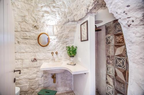 une salle de bain avec un lavabo et un mur en pierre dans l'établissement Trulli cicale e olive - Le Case di Valentina, à Ceglie Messapica