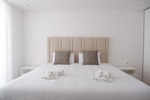 a large white bed with two pillows on it at T3 Baía de São Martinho in São Martinho do Porto
