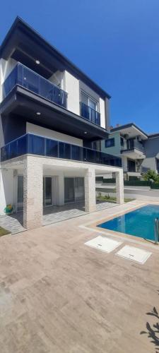a large house with a swimming pool in front of it at Soğucak Villa in Kuşadası