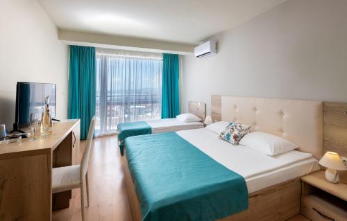 a bedroom with two beds and a desk and a television at Sea View Hills in Sveti Vlas