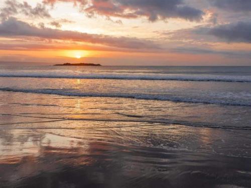a sunset on a beach with the ocean at Point Village Hotel and Self Catering in Mossel Bay