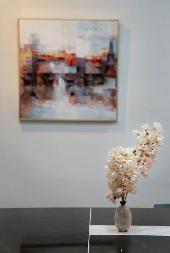 a vase with flowers on a table in front of a painting at satun muslimhome in Ban Khao Khrai