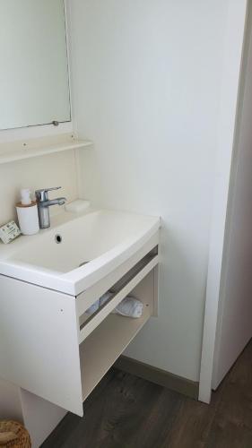 une salle de bain avec un lavabo blanc et un miroir dans l'établissement Mobilhomelaco34siblu, à Valras-Plage