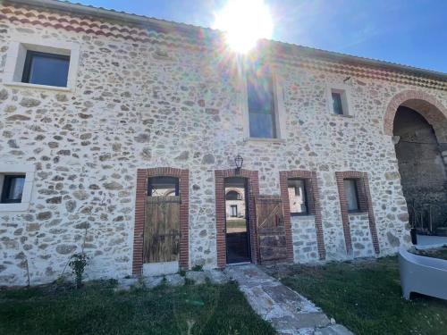 un bâtiment en pierre avec le soleil brillant sur lui dans l'établissement La Métairie du Château Paul, à Aussillon