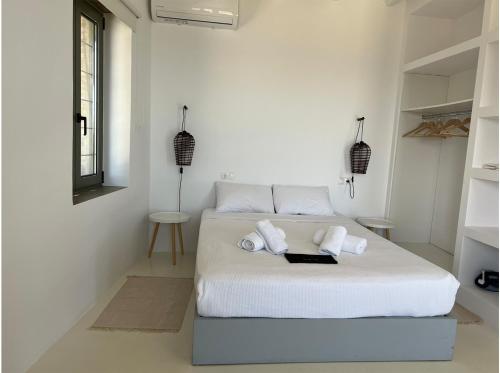 a white bedroom with a bed with towels on it at La Priva Calma in Agios Ioannis
