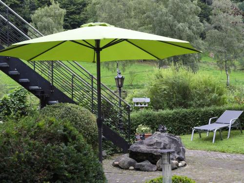 a green umbrella in a garden with a bench at Ferienwohnungen Familie Schauerte in Schmallenberg