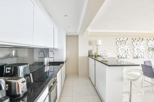 une cuisine avec des comptoirs noirs et des armoires blanches dans l'établissement Appart belle vue mer et plage proche de Monaco, à Cap d'Ail