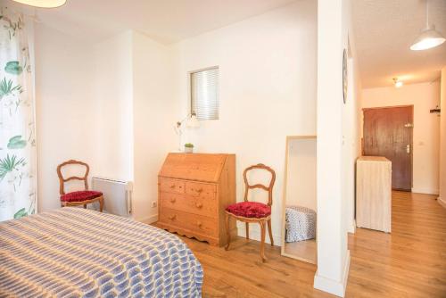 - une chambre avec deux chaises, un lit et une commode dans l'établissement Appartement Cosy Proche plage, à Santa-Maria-di-Lota