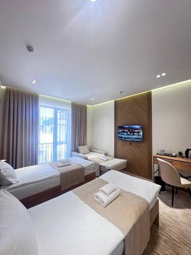 a hotel room with three beds and a desk at North Star Hotel in Yakkasaray