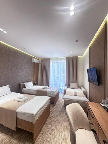 a hotel room with three beds and a flat screen tv at North Star Hotel in Yakkasaray
