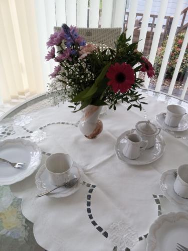 a white table with a vase of flowers on it at Ferienhaus Mooi Huus 95157 in Rhauderfehn
