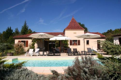 une maison avec une piscine, des chaises et des parasols dans l'établissement Maison Périgourdine au calme, à Saint-Cybranet