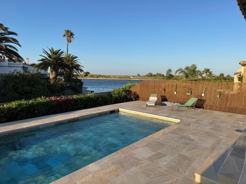 - une piscine dans un jardin avec vue sur l'eau dans l'établissement Villa Moana Lagune, à Saint-Cyprien
