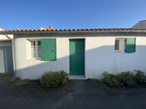 une maison blanche avec une porte verte et 2 fenêtres dans l'établissement La maison des Boutons d Or, à Sainte-Marie de Ré