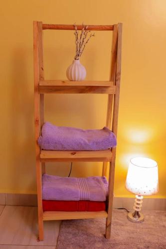 a wooden shelf with purple cushions next to a lamp at Luna spa and Lodges in Kabuga