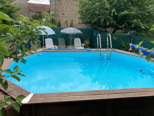 une grande piscine bleue avec une terrasse en bois dans l'établissement La Maison Glycine, à La Villedieu