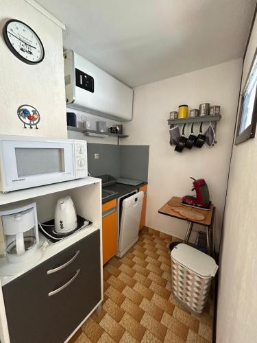 une petite cuisine avec un micro-ondes et une table dans l'établissement L'Escapade de Jules, au Cap d'Agde
