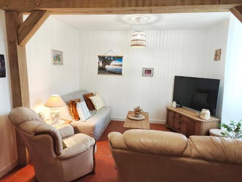 a living room with a couch and a tv at Gîte Chez Renée in Azay-le-Ferron