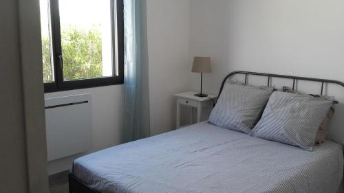 Cette chambre comprend un lit avec deux oreillers et une fenêtre. dans l'établissement Nice apartment with garden, à Agde