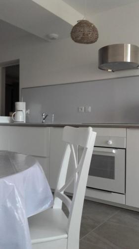 une chaise blanche assise dans une cuisine avec un évier dans l'établissement Nice apartment with garden, à Agde