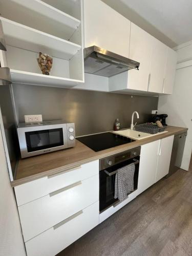 une cuisine avec des armoires blanches et un micro-ondes dans l'établissement Le Poitevin Garden View Center31, à Niort