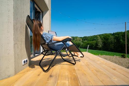 a woman sitting in a chair on a porch at Bunkier House in Niedźwiada
