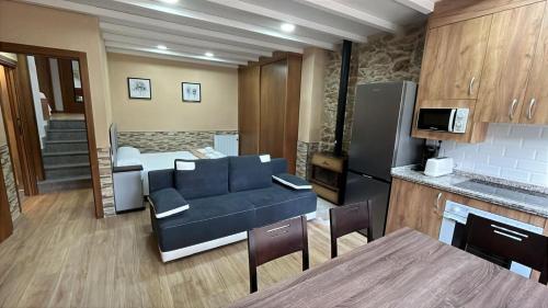 a living room with a blue couch and a kitchen at Mar de Nubes Piornal 1 in Piornal
