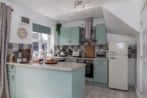 a kitchen with blue cabinets and a white refrigerator at Countryside Stay Near JCB, Peaks & Alton Towers in Rocester