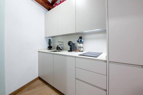 a white kitchen with white cabinets and a wooden floor at Miravilla 25 Potes 1 in Potes