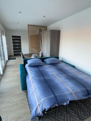 - un grand lit dans une chambre avec une couverture bleue dans l'établissement studio dans une dependance, à La Celle-sous-Gouzon