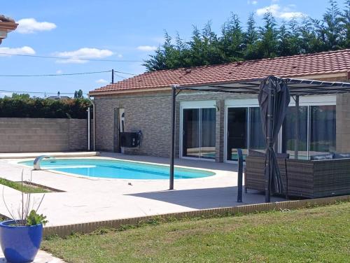- une piscine avec un parasol à côté d'une maison dans l'établissement studio dans une dependance, à La Celle-sous-Gouzon