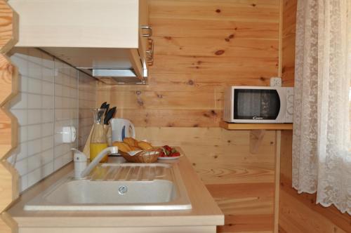 a small kitchen with a sink and a microwave at Stacja Lato domki dla rodzin z dziećmi in Mikołajki