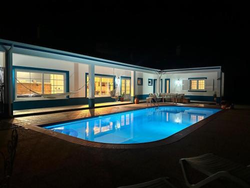 a large swimming pool in a house at night at Villa Rio in Praia do Ribatejo