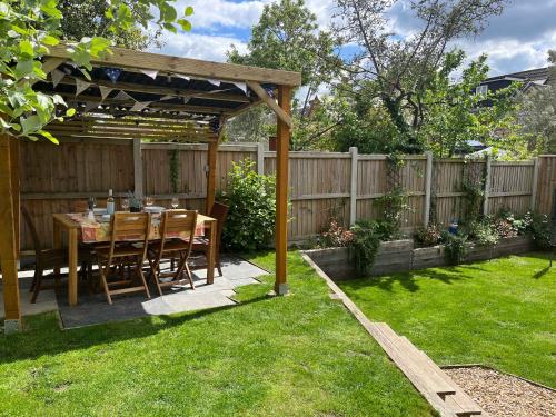 einen Esstisch unter einer Pergola im Hinterhof in der Unterkunft Charlotte Cottage - Minutes from Poole Park, with Feature Log Burner in Poole